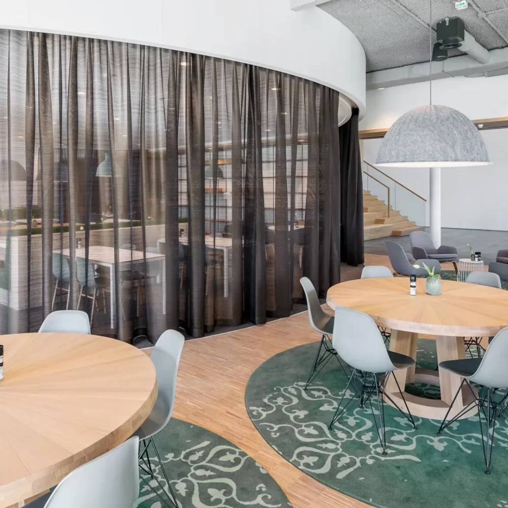 Interieurontwerp werkcafé met rond verlaagd wit plafond en ronde tafels met Vitra stoelen