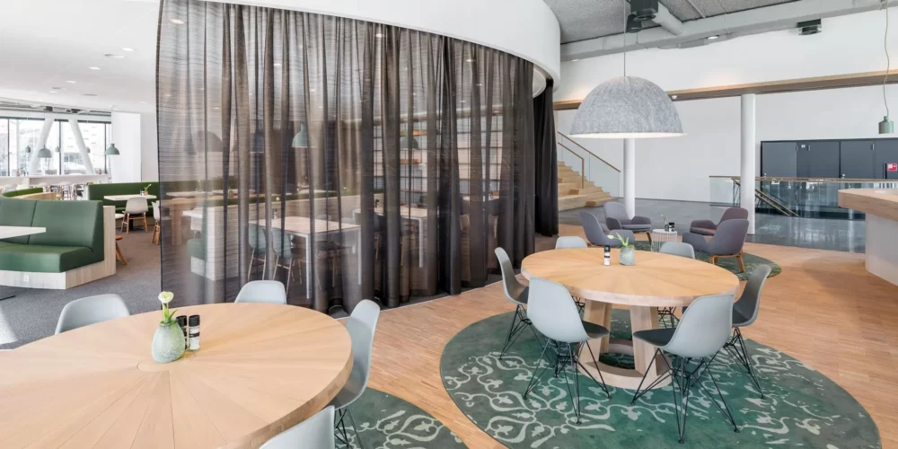 Interieurontwerp werkcafé met rond verlaagd wit plafond en ronde tafels met Vitra stoelen