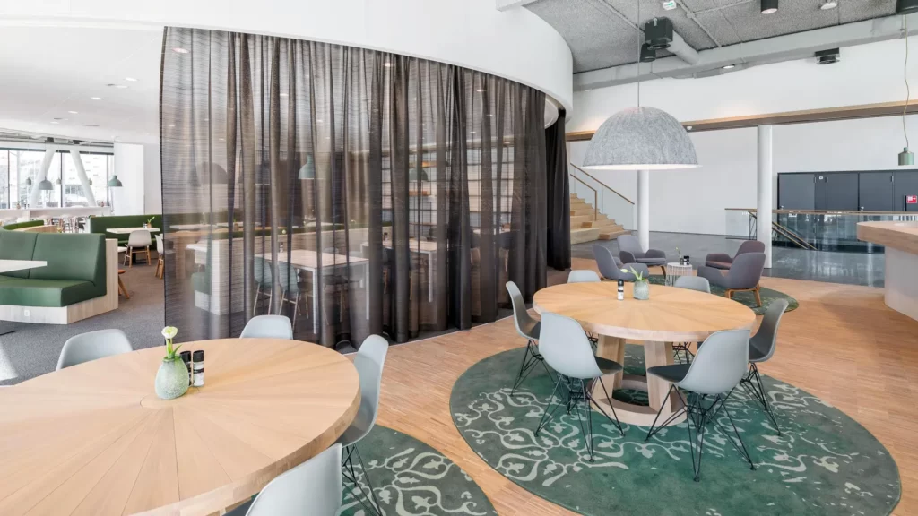 Interieurontwerp werkcafé met rond verlaagd wit plafond en ronde tafels met Vitra stoelen