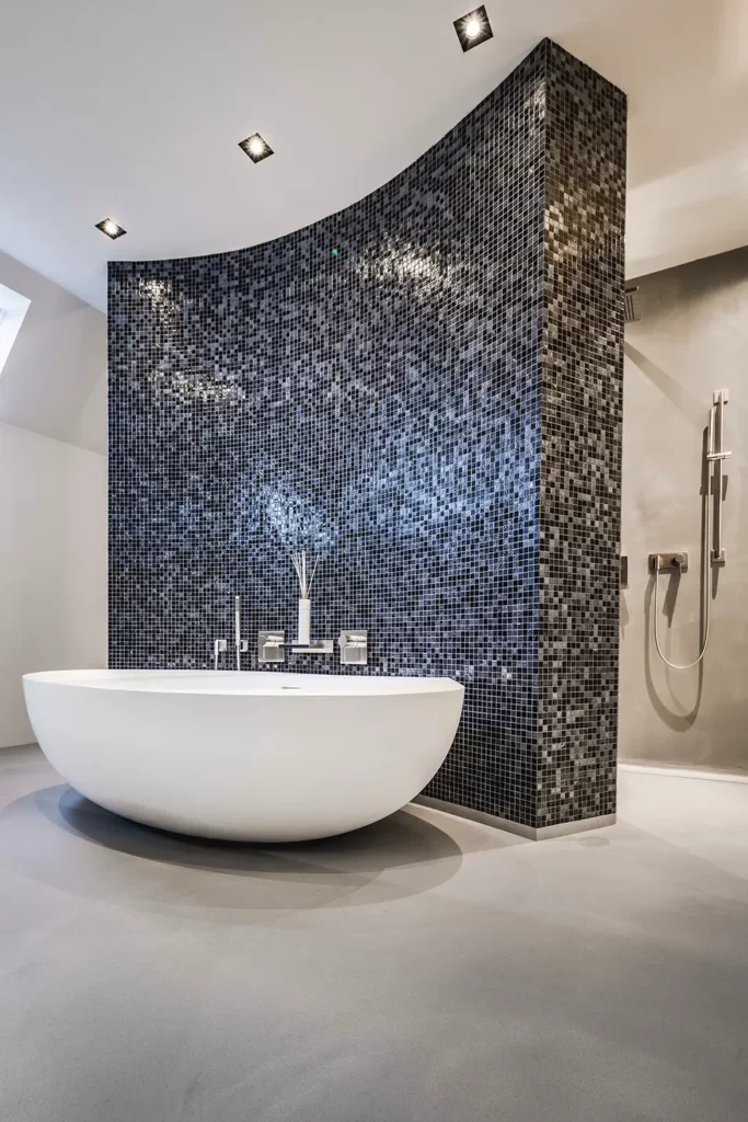Luxe badkamer met gietvloer en ronde mozaïek wand om vrijstaand ovalen ligbad