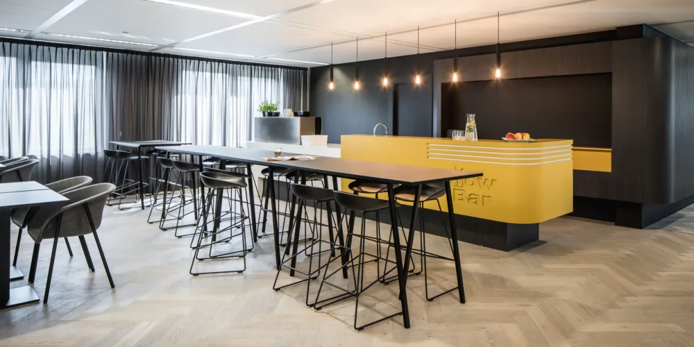 interieurontwerp lunchruimte met yellow bar en zwarte lunchtafels en stoelen