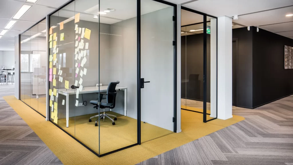 kantoorinrichting met gele vloerbedekking in transparante stilteruimten