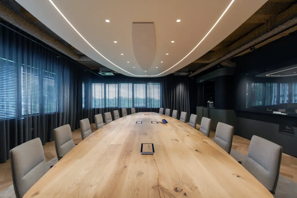 Lange eiken vergadertafel met geïntegreerde aansluitpunten in executive boardroom