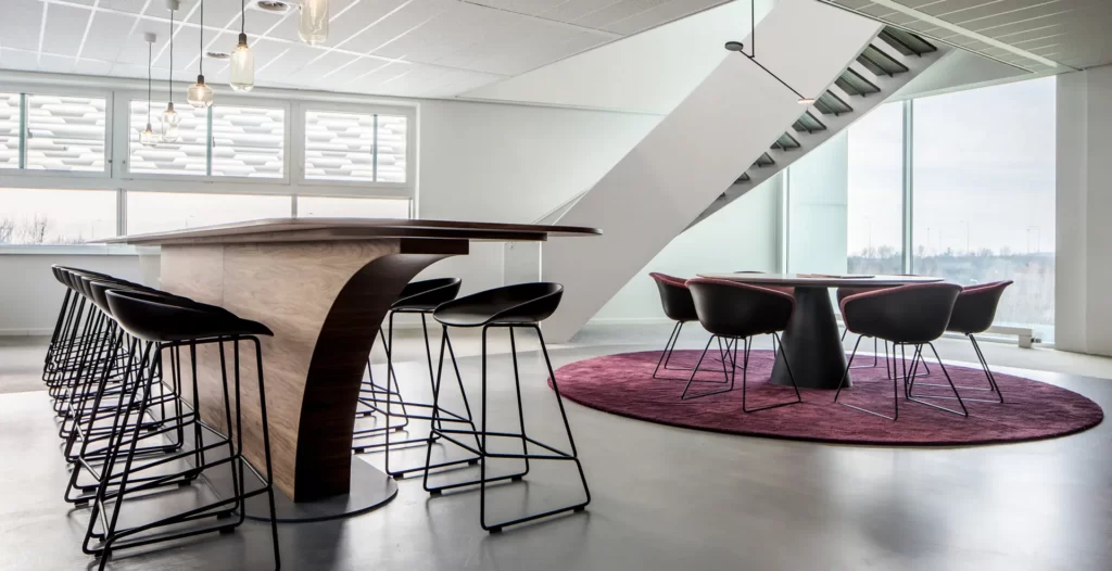 Coffee corner op kantoorverdieping met overlegplekken en speciaal ontworpen gekromde trap
