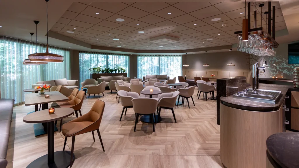 Koffiekamer in Crematorium Venlo met hanglampen, houten vloer en geïntegreerde spoelbak bij de bar.