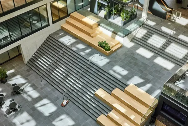 Plamen van Dijk | Design Studio, diagonaal overzicht van een interieurontwerp in een atrium met houten zitelementen op de trap