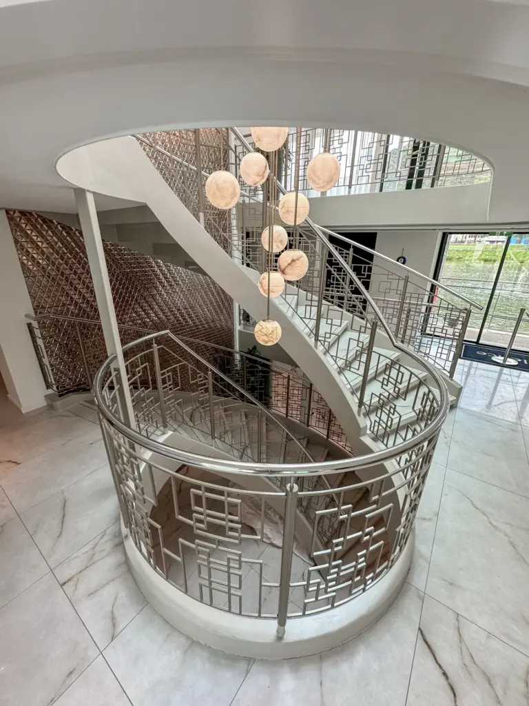 Bovenaanzicht van het centrale trappenhuis van de Excellence Crown, waarin de vloeiende trapvorm, open vide en geometrisch vormgegeven balustrades samen een heldere routing en sterke ruimtelijke identiteit creëren.